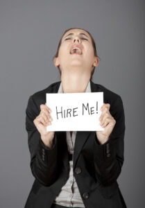 Business woman holding a card board with the text message "Hire me" and beging for a job.